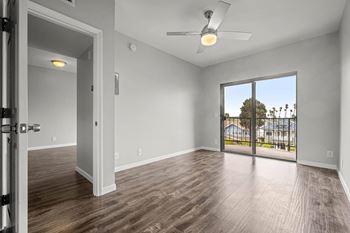 A room with a ceiling fan and sliding glass doors leading to a balcony.